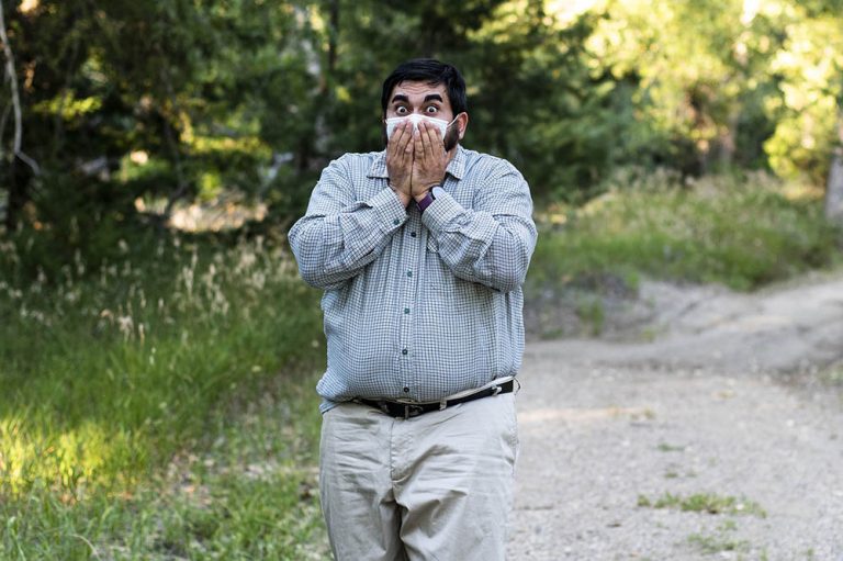 A man, wearing a medical mask, looking shocked or surprised