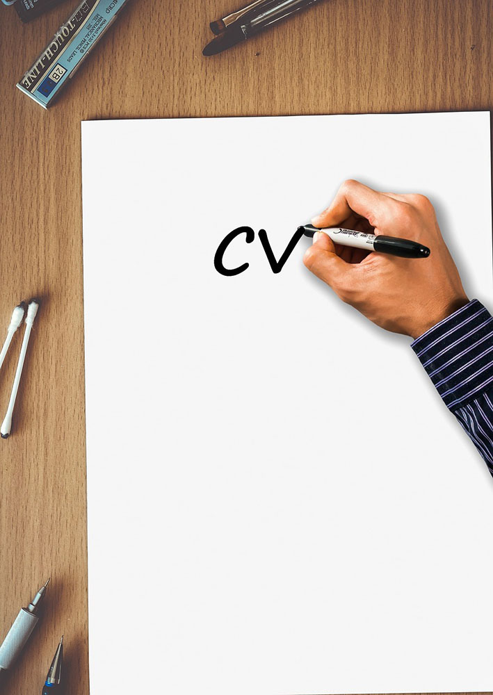 A hand writing the letters CV with a sharpie pen on a large white sheet of paper